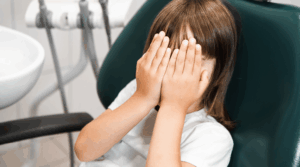Child covering their face at the dentist.