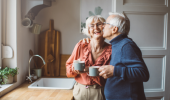 Older couple smiling and drinking coffee.