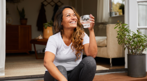 Person drinking water while smiling and laughing.