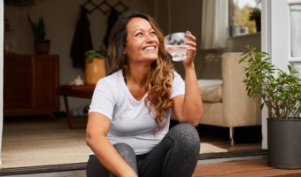 Person drinking water while smiling and laughing.