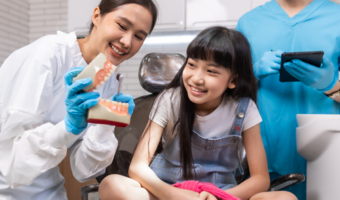 Dentist teaching child about oral health and brushing teeth.