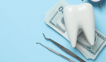 Fake tooth, money and dental equipment on a table.