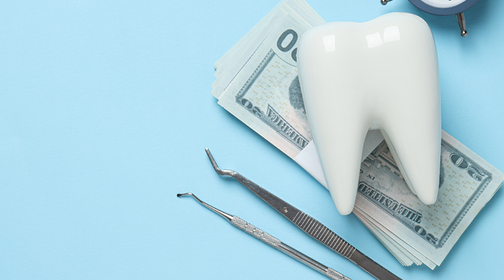 Fake tooth, money and dental equipment on a table.
