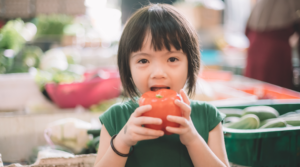 Child eating an apple at the farmers market.