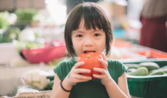 Child eating an apple at the farmers market.