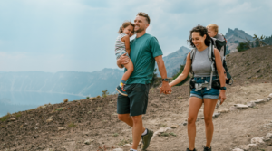 Couple smiling and hiking with their children.