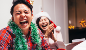 Two friends laughing and smiling with holiday clothes on.