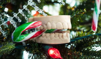 Ornament of a tooth mold, biting down on a candy cane.