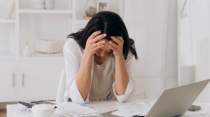 Person looking over paperwork, holding their hands to their head in stress.