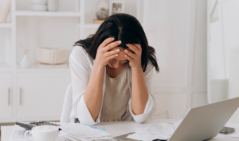 Person looking over paperwork, holding their hands to their head in stress.