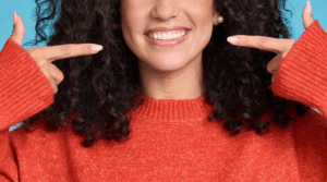 Person pointing at their smile.