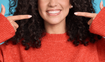 Person pointing at their smile.
