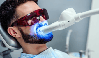 Person doing a teeth whitening procedure at the dentist.