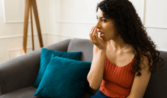 Person holding their hand to their mouth, smelling their breath.